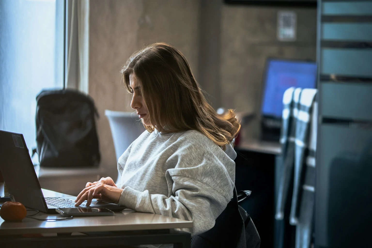 Una professionista lavora al computer accanto a una finestra.