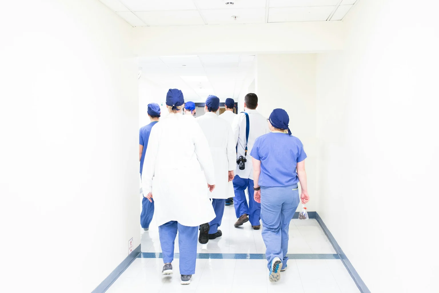 Un gruppo di professionisti sanitari percorre un corridoio ospedaliero.
